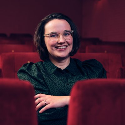 Anna Schoeppe sitzt in einem Kinosaal und lächelt in die Kamera