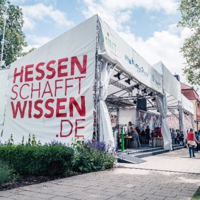Eine Bühne die mit Planen bedeckt ist, auf denen &quot;Hessen schafft Wissen.de&quot; steht