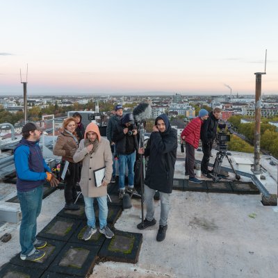 Eine Kameracrew steht auf einem Dach und überblickt eine Stadt