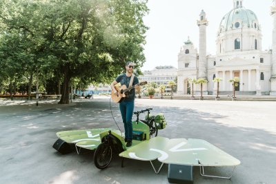 Eine Person steht draußen auf einer Bühne und spielt Gitarre