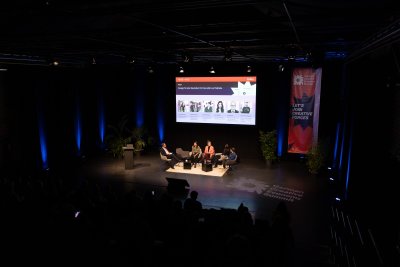 Vier Frauen sitzen im Panel, ein Mann moderiert
