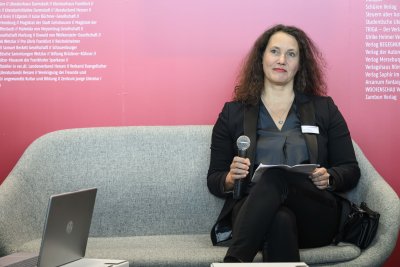 Frau auf Sofa sitzend mit Mikrofon in der Hand