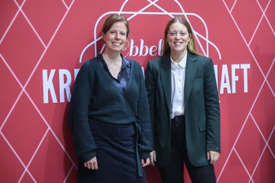 Zwei Frauen stehen vor roter Wand