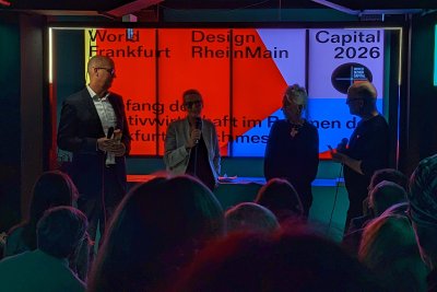 vier Personen stehen auf einer Art Bühne, eine Person mit Mikro