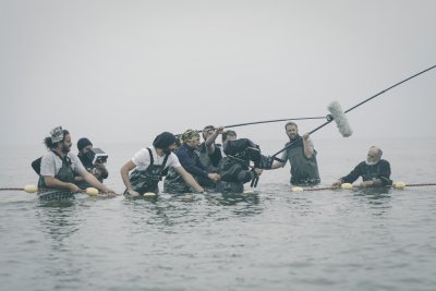 Kameracrew steht hüftentief im Wasser und filmt einen Darsteller