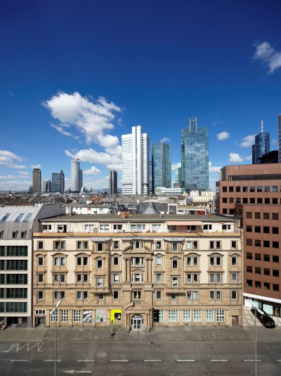 Bild eines alten Gebäudes im Frankfurter Bahnhofsviertel, im Hintergrund ragt die Frankfurter Skyline hinaus