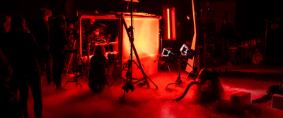 Ein dunkles, vernebeltes Filmset wird mit roten Lichtern angestrahlt