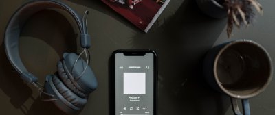 Vogelperspektive eines Tisches, auf dem ein Handy, Kopfhörer und eine Tasse steht